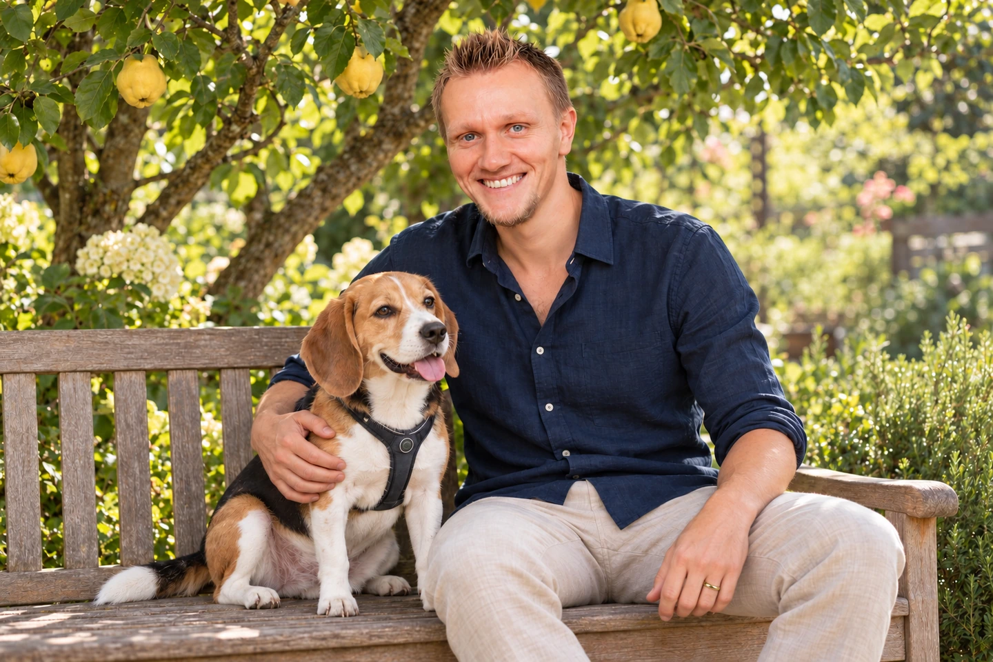 Christopher Kessler sitzt mit seinem Hund Taiga auf einer Gartenbank unter einem Quittenbaum.